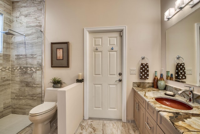 bathroom featuring vanity, toilet, and tiled shower