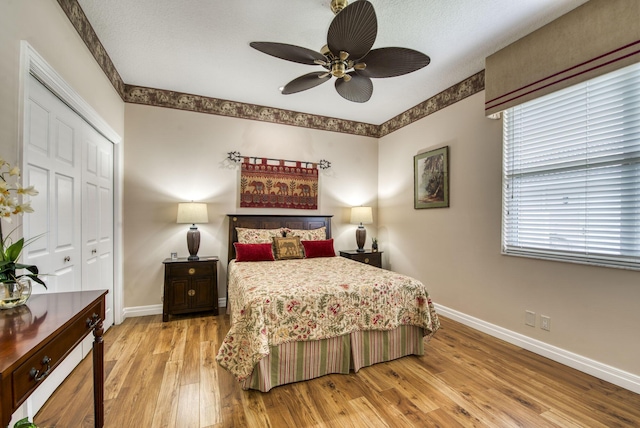 bedroom featuring a closet, baseboards, light wood-style flooring, and a ceiling fan