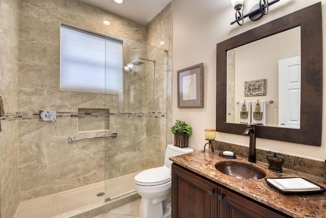 bathroom with tile patterned flooring, tiled shower, toilet, and vanity