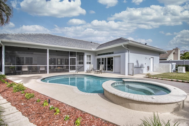 view of pool featuring fence, a pool with connected hot tub, central AC, a sunroom, and a patio area