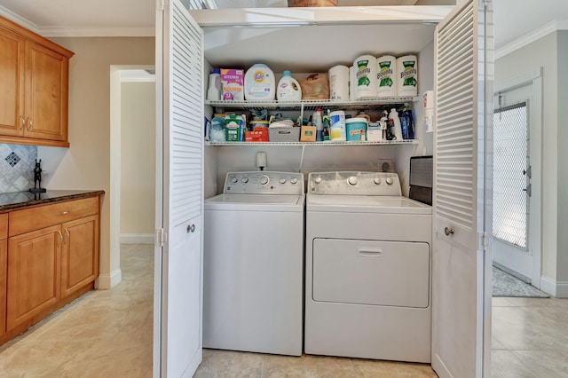 laundry area with crown molding, washer and dryer, and light tile patterned flooring