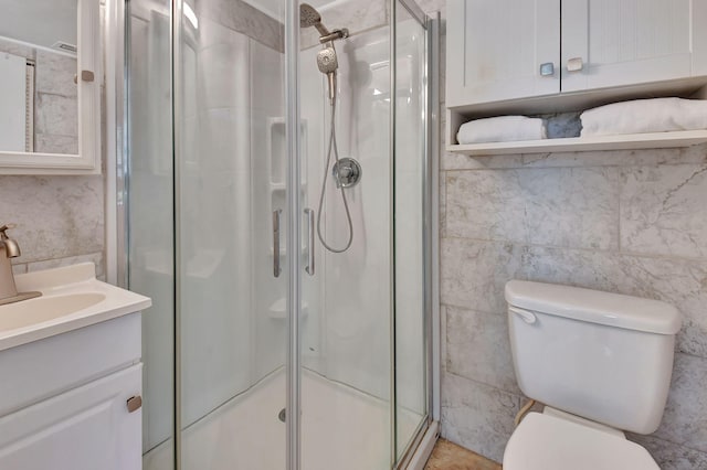 bathroom with a shower with door, vanity, and toilet