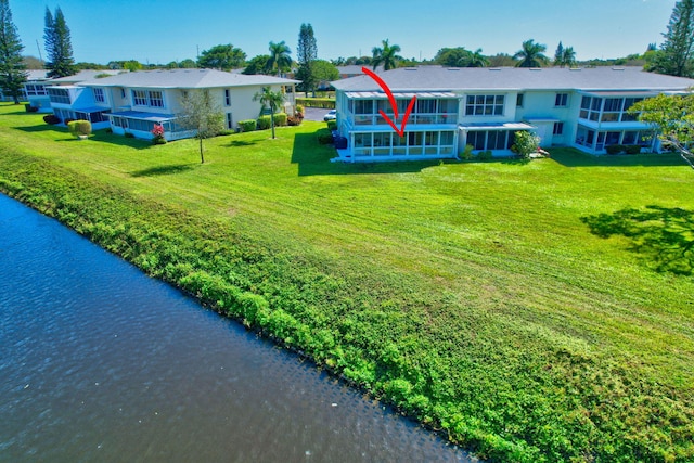 rear view of property featuring a water view and a lawn