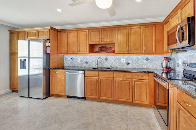 kitchen featuring appliances with stainless steel finishes, sink, dark stone counters, ceiling fan, and crown molding