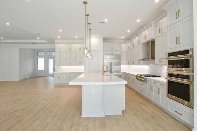 kitchen with white cabinetry, appliances with stainless steel finishes, a large island, and wall chimney range hood