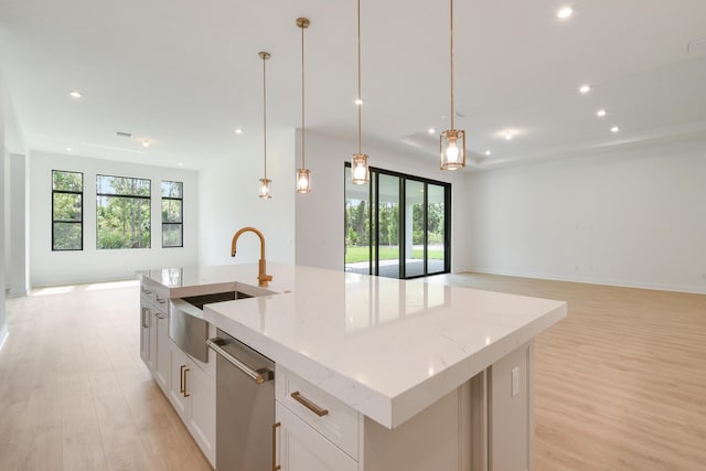 kitchen with pendant lighting, light stone countertops, an island with sink, white cabinets, and stainless steel dishwasher