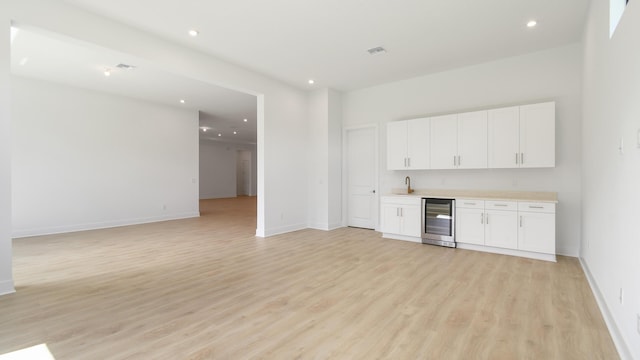 bar featuring white cabinetry, sink, light hardwood / wood-style flooring, and wine cooler