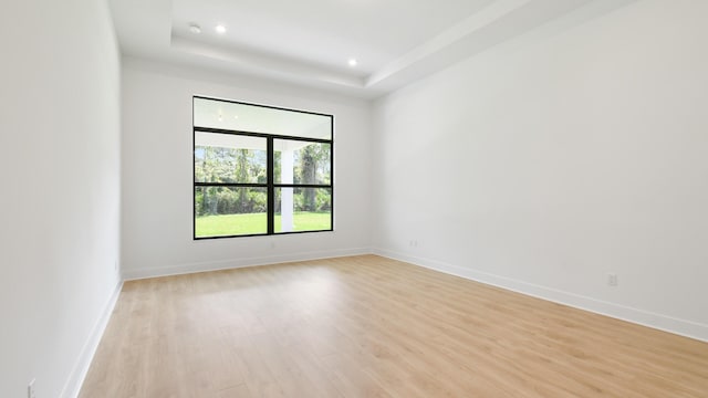 unfurnished room featuring light hardwood / wood-style flooring and a tray ceiling