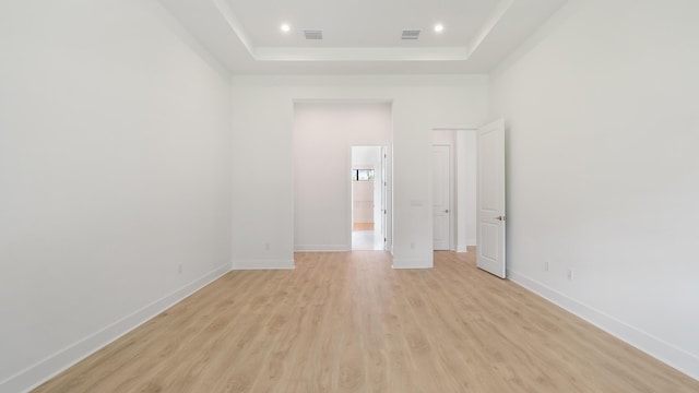 empty room featuring a tray ceiling and light hardwood / wood-style flooring