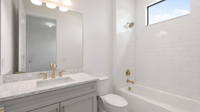 full bathroom featuring vanity, tiled shower / bath combo, and toilet