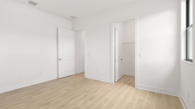 unfurnished bedroom with a spacious closet and light hardwood / wood-style flooring