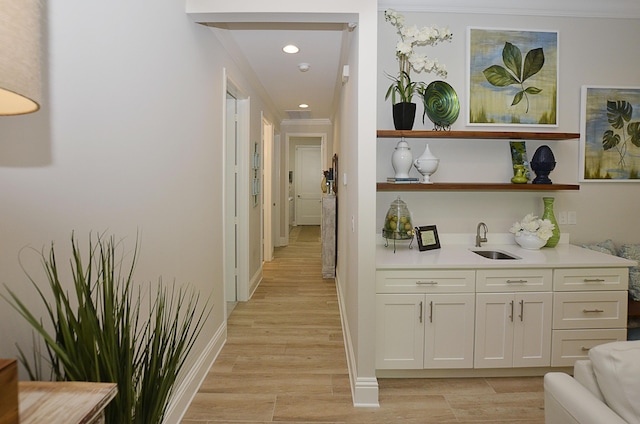 hallway featuring ornamental molding, light hardwood / wood-style floors, and sink