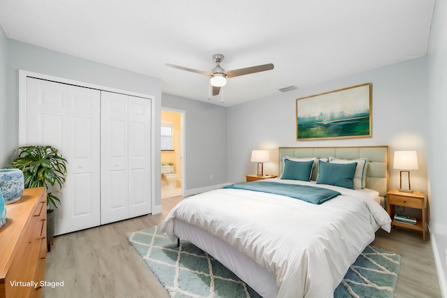 bedroom with ensuite bath, light wood-type flooring, ceiling fan, and a closet