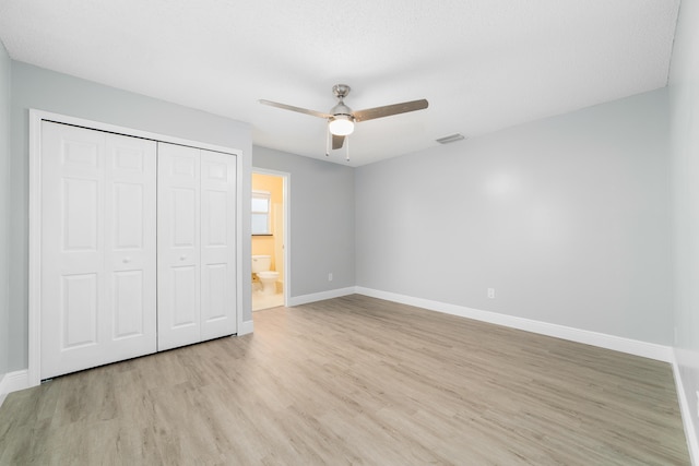 unfurnished bedroom with ceiling fan, ensuite bath, light hardwood / wood-style floors, and a closet