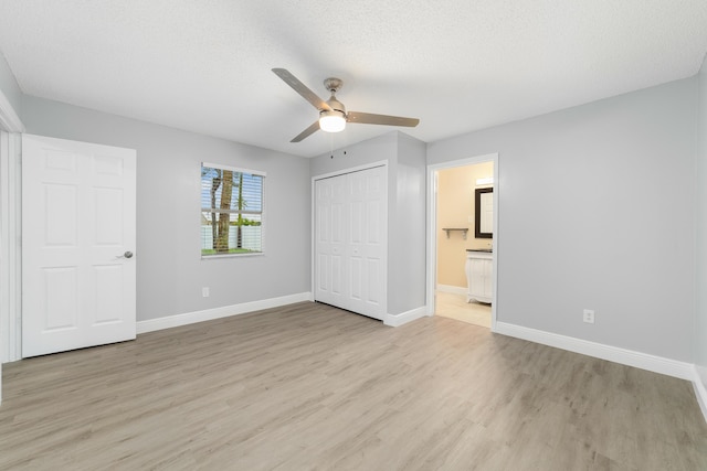 unfurnished bedroom with ensuite bathroom, a closet, ceiling fan, a textured ceiling, and light hardwood / wood-style flooring