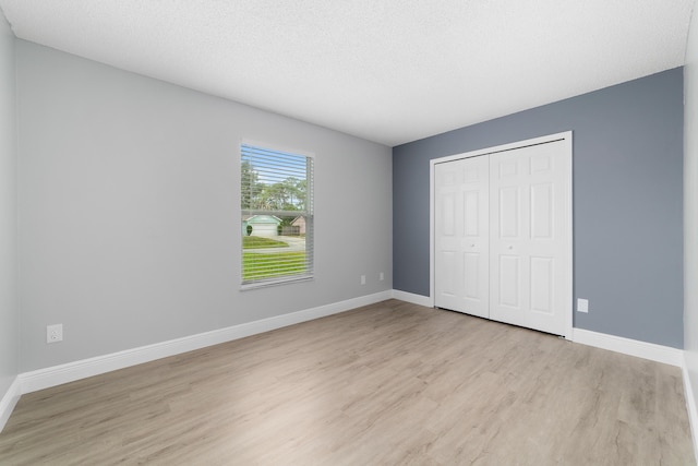 unfurnished bedroom featuring light hardwood / wood-style flooring, a textured ceiling, and a closet