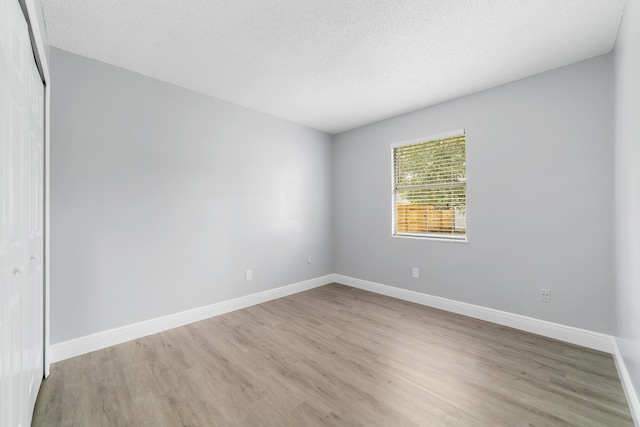 unfurnished room featuring a textured ceiling and light wood-type flooring