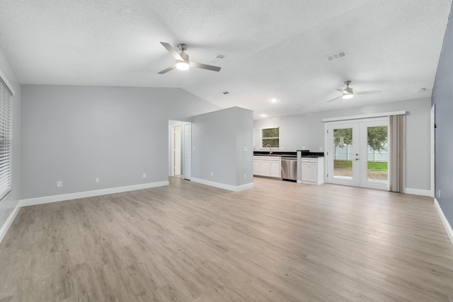 unfurnished living room featuring french doors, ceiling fan, light hardwood / wood-style floors, and vaulted ceiling