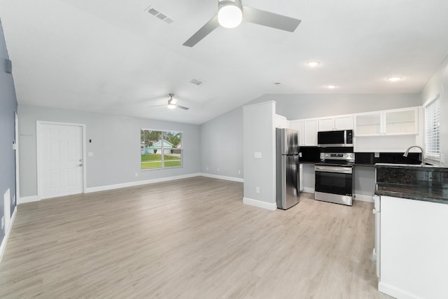 kitchen featuring ceiling fan, stainless steel appliances, white cabinets, vaulted ceiling, and light wood-type flooring