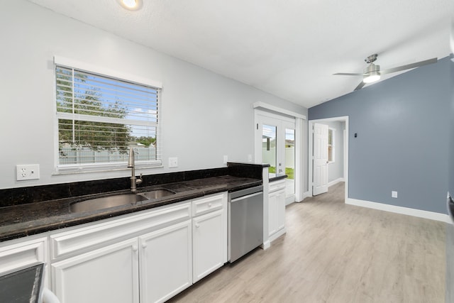 kitchen featuring lofted ceiling, sink, dishwasher, dark stone counters, and white cabinets