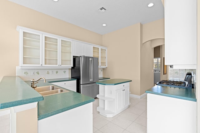 kitchen featuring tasteful backsplash, white cabinetry, sink, stainless steel fridge, and kitchen peninsula