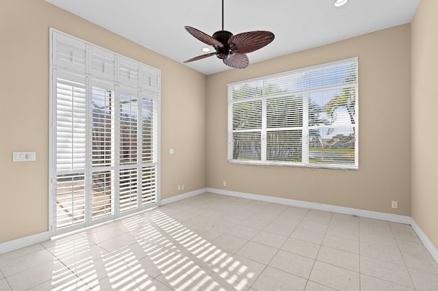 empty room featuring ceiling fan, plenty of natural light, and light tile patterned floors