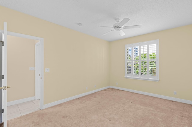 empty room with ceiling fan, light carpet, and a textured ceiling