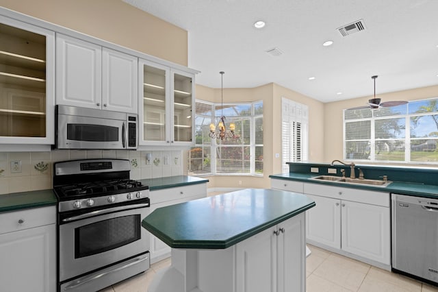 kitchen featuring decorative light fixtures, tasteful backsplash, sink, white cabinets, and stainless steel appliances