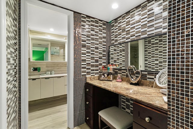 bathroom featuring hardwood / wood-style floors, vanity, and tile walls