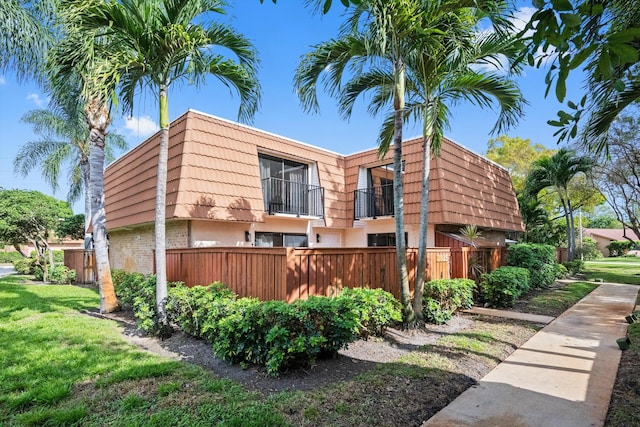 view of home's exterior with a balcony and a lawn