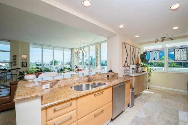 kitchen with sink, dishwasher, hanging light fixtures, light stone countertops, and light brown cabinets