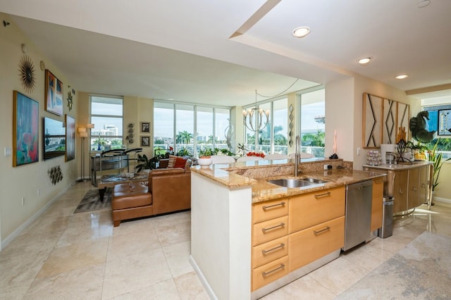 kitchen with sink, light brown cabinets, stainless steel dishwasher, light stone countertops, and a center island with sink