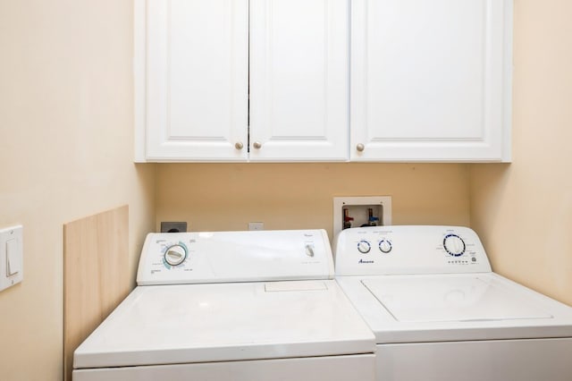 clothes washing area featuring cabinets and washer and dryer