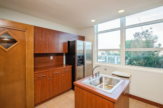 kitchen featuring a kitchen island with sink, sink, and stainless steel fridge with ice dispenser