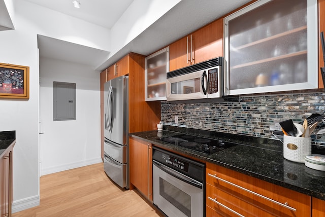 kitchen with decorative backsplash, electric panel, dark stone counters, and appliances with stainless steel finishes