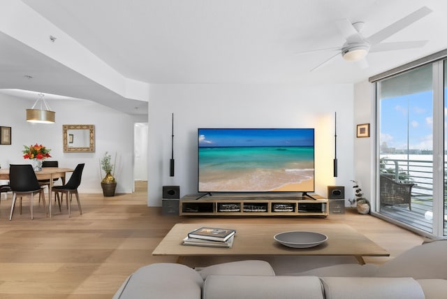 living room featuring ceiling fan, floor to ceiling windows, and wood-type flooring