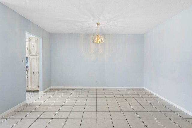 180 High Point Ter E Unit C, Delray Beach, FL 33445 - empty room featuring a chandelier, a textured ceiling, baseboards, and light tile patterned floors