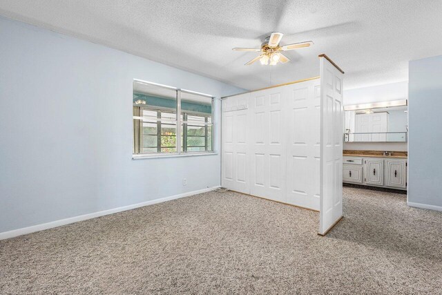 180 High Point Ter E Unit C, Delray Beach, FL 33445 - unfurnished bedroom featuring carpet floors, baseboards, a textured ceiling, a closet, and a ceiling fan
