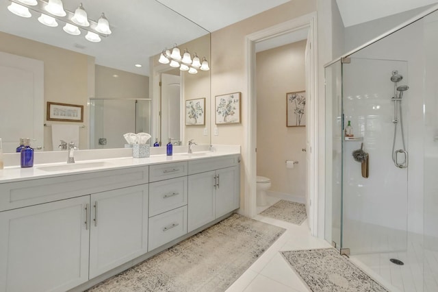 bathroom with tile patterned flooring, vanity, a shower with shower door, and toilet