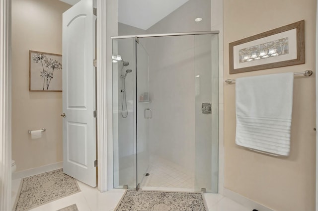 bathroom featuring toilet, lofted ceiling, a shower with door, and tile patterned flooring