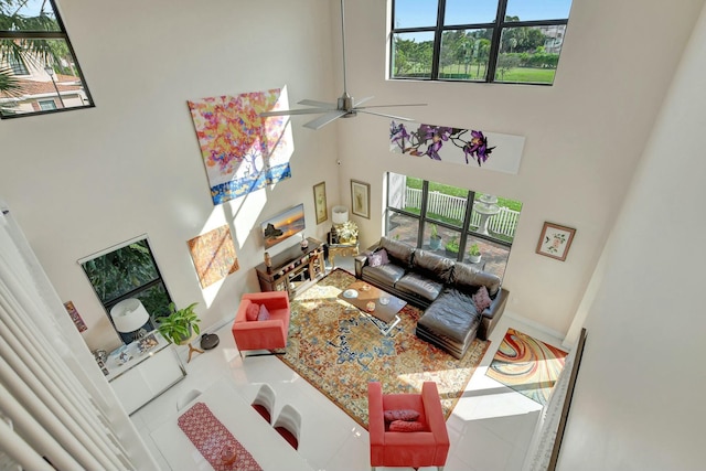 tiled living room with ceiling fan, a towering ceiling, and a healthy amount of sunlight