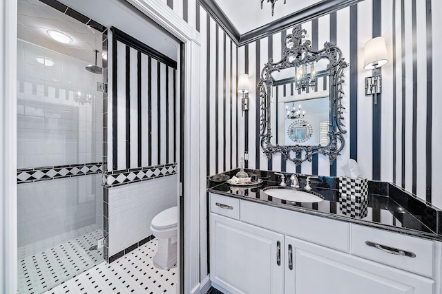 bathroom with a tile shower, vanity, tile patterned flooring, and toilet