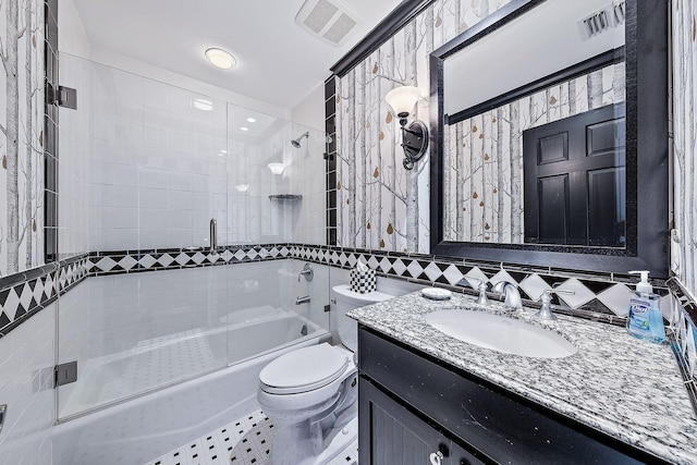 full bathroom featuring toilet, combined bath / shower with glass door, tile walls, vanity, and tile patterned flooring