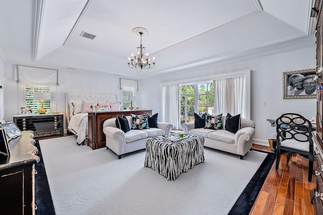 bedroom with a notable chandelier, a tray ceiling, wood-type flooring, and ornamental molding