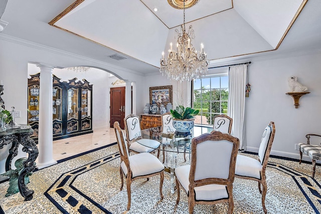 dining room featuring a tray ceiling, crown molding, a chandelier, and ornate columns