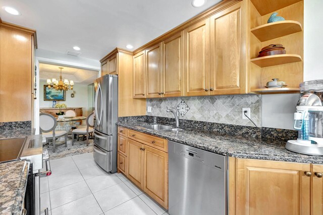 kitchen featuring sink, light tile patterned floors, dark stone counters, stainless steel appliances, and backsplash