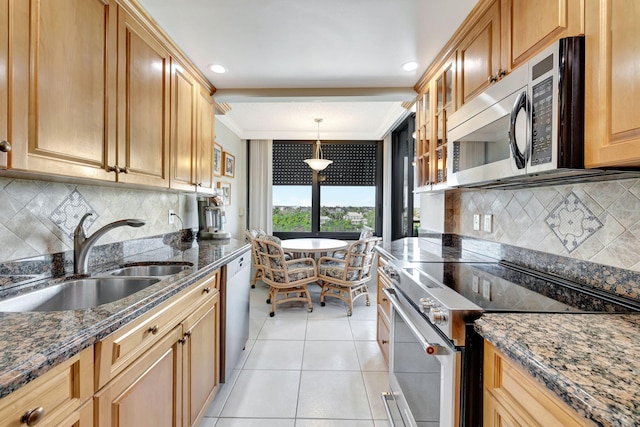 kitchen with sink, light tile patterned floors, dark stone countertops, stainless steel appliances, and decorative light fixtures