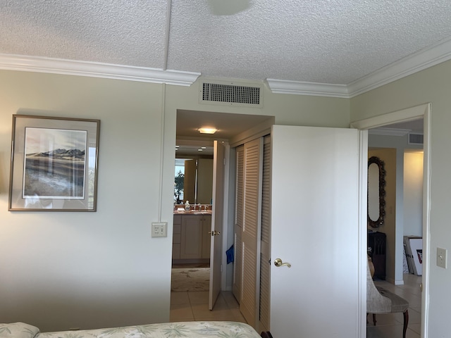 bedroom with ornamental molding, a textured ceiling, a closet, and light tile patterned floors