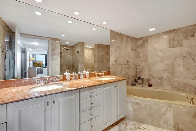 bathroom featuring independent shower and bath, vanity, and tile walls