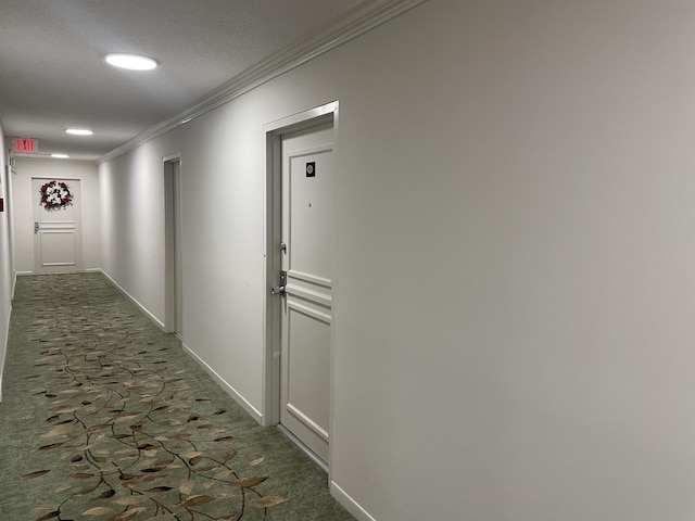 hallway with crown molding and dark colored carpet